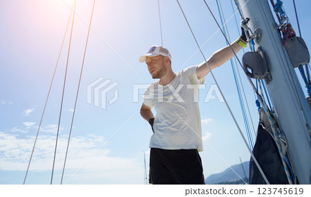 Male captain stands proudly on a sailboat enjoying the moment 123745619