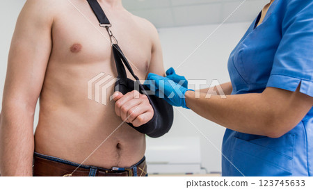 Nurse putting a sling on patients arm that is broken. Injury Nurse putting a sling on patients arm that is broken. Injury 123745633