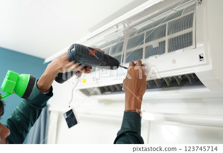 The worker cleans and repairs the air conditioner to ensure it operates properly 123745714
