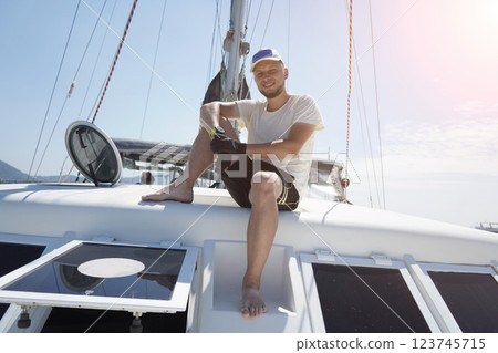 A man is calmly sitting on the deck of a beautiful sailboat 123745715