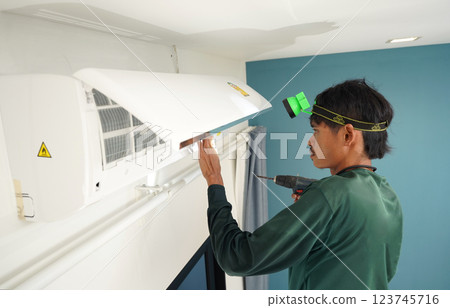 The worker cleans and repairs the air conditioner to ensure it operates properly 123745716