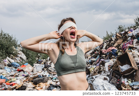 A blindfolded female volunteer screams from powerlessness in a dump of plastic A blindfolded female volunteer screams from powerlessness in a dump of plastic 123745733