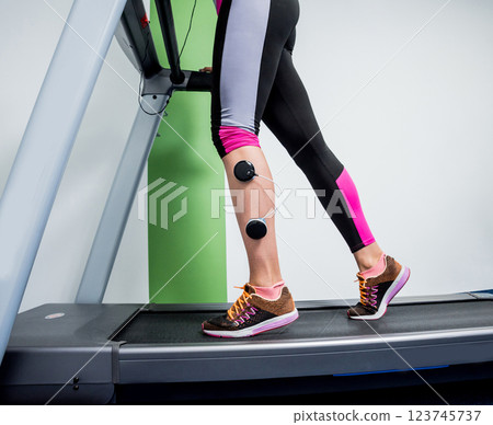 Young sports woman with electrostimulator on the muscles of the legs.  123745737