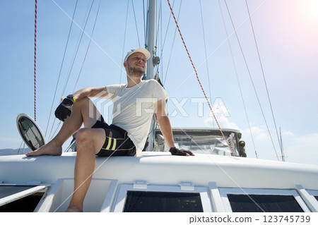 A man is calmly sitting on the deck of a beautiful sailboat 123745739