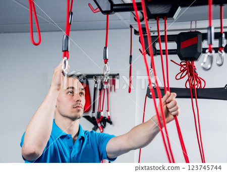 Physiotherapy. Suspension training therapy. Young man doing fitness traction 123745744