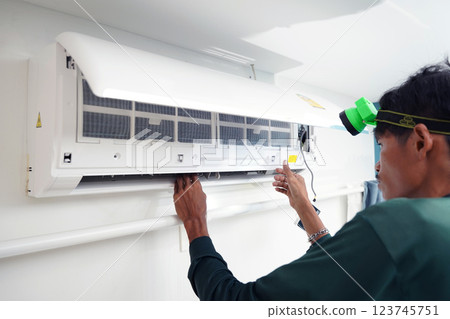 The worker cleans and repairs the air conditioner to ensure it operates properly The worker cleans and repairs the air conditioner to ensure it operates properly 123745751