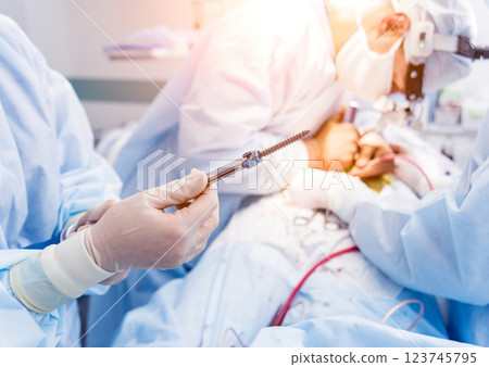 Spinal surgery. Surgeon show polyaxial screw in operating room  123745795