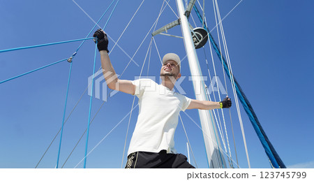 Male captain stands proudly on a sailboat enjoying the moment 123745799