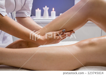 Beautiful young woman enjoying legs massage with oil in spa salon. Cosmetology Beautiful young woman enjoying legs massage with oil in spa salon. Cosmetology 123745814