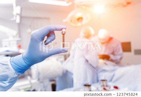Spinal surgery. Surgeon show polyaxial screw in operating room Spinal surgery. Surgeon show polyaxial screw in operating room 123745824