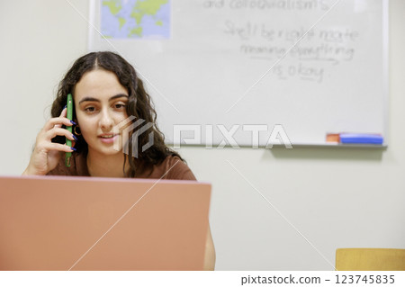 A woman talking on the phone while using a computer A woman talking on the phone while using a computer 123745835
