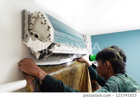 The worker cleans and repairs the air conditioner to ensure it operates properly The worker cleans and repairs the air conditioner to ensure it operates properly 123745853