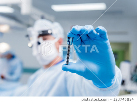 Spinal surgery. Surgeon show polyaxial screw in operating room Spinal surgery. Surgeon show polyaxial screw in operating room 123745854