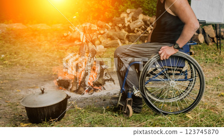 Disabled man resting in a campsite with friends. Wheelchair in the forest Disabled man resting in a campsite with friends. Wheelchair in the forest 123745870