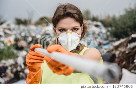 Woman volunteer helps clean the field of plastic garbage.  123745906