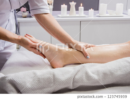 Beautiful young woman enjoying foot massage in spa salon. Cosmetology Beautiful young woman enjoying foot massage in spa salon. Cosmetology 123745939