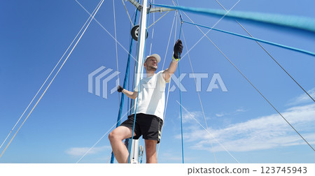 Male captain stands proudly on a sailboat enjoying the moment Male captain stands proudly on a sailboat enjoying the moment 123745943