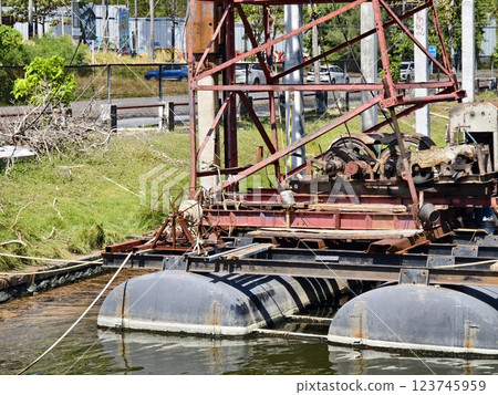 A large metal construction crane is in the middle of a body of water 123745959