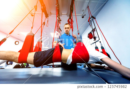 Physiotherapy. Suspension training therapy. Young man doing fitness traction 123745982