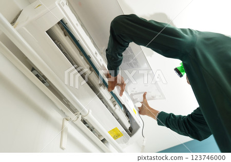 The worker cleans and repairs the air conditioner to ensure it operates properly The worker cleans and repairs the air conditioner to ensure it operates properly 123746000