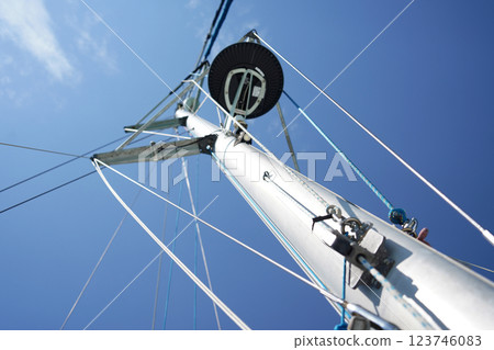 Tall sturdy mast of a sailboat stands out vividly against the bright blue sky. 123746083