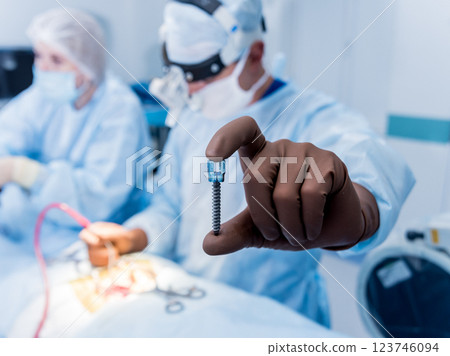 Spinal surgery. Surgeon show polyaxial screw in operating room 123746094
