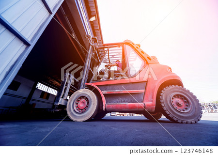 The big industrial forklift drives into the warehouse. The big industrial forklift drives into the warehouse. 123746148