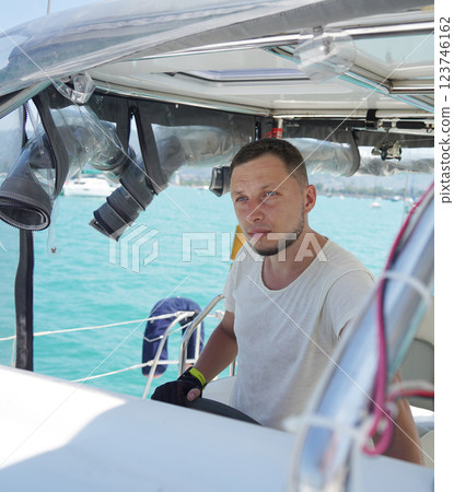 Young male captain in black gloves steering voyage boat 123746162