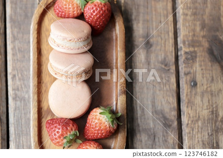 Strawberry macaroons and strawberries with stems on a wooden plate 123746182
