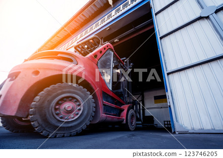 The big industrial forklift drives into the warehouse. 123746205