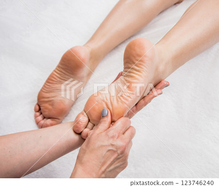 Beautiful young woman enjoying foot massage in spa salon. Cosmetology 123746240