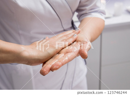 Masseur putting aroma oil on her hands, preparing for massage in spa center Masseur putting aroma oil on her hands, preparing for massage in spa center 123746244