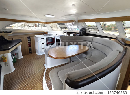 A cozy living room and kitchen featuring a stylish curved couch and a table located on sailing boat 123746283