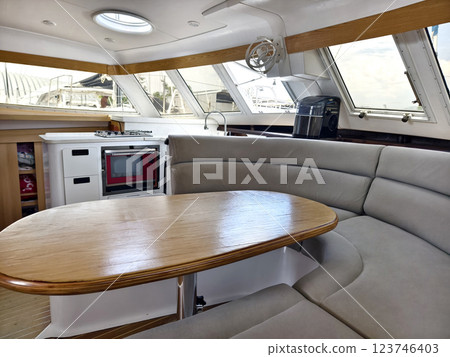 A cozy living room and kitchen featuring a stylish curved couch and a table located on sailing boat 123746403