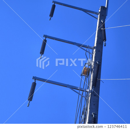 Men in work clothes and hard hats are installing high-voltage wires on a power pole 123746411