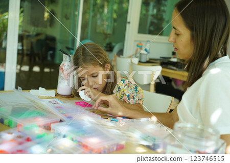 Teacher in workshop teched two girls how to assemble a thermo mosaic Teacher in workshop teched two girls how to assemble a thermo mosaic 123746515