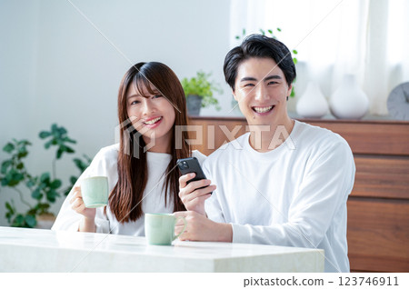 Smiling man and woman holding smartphones in the living room Smiling man and woman holding smartphones in the living room 123746911