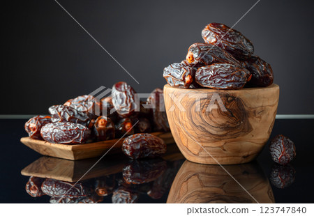 Dates in wooden dish on a black background. 123747840
