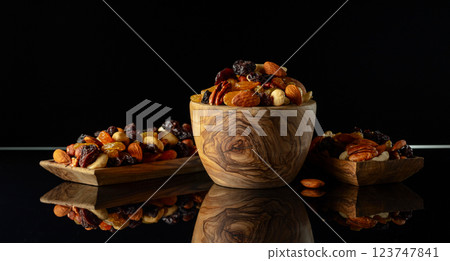 Mix of various nuts and raisins on a black reflective background. 123747841