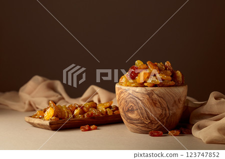 Yellow sultana raisins in a wooden bowl on a beige background. 123747852