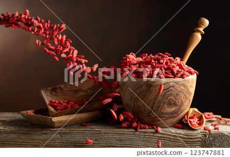 Dried goji berries in wooden bowl on a brown background. 123747881