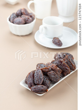 Dates in white dish on a beige background. 123747884