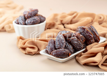 Dates in white dish on a beige background. 123747885