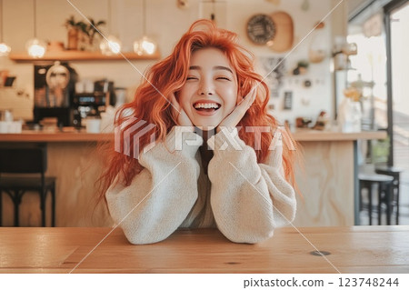 Joyful young woman with red hair enjoys time at a cozy cafe during the afternoon Joyful young woman with red hair enjoys time at a cozy cafe during the afternoon 123748244