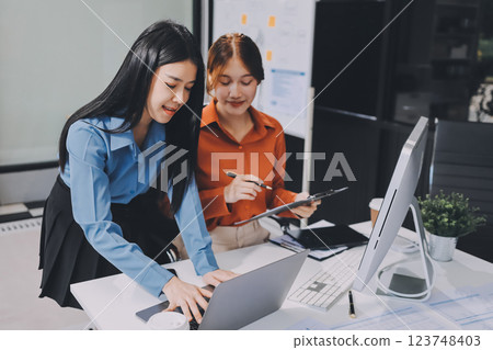 Entrepreneur Asian businessman and businesswoman discussing new business project in tablet in modern Meeting In Modern Office, Asian business casual concept. 123748403