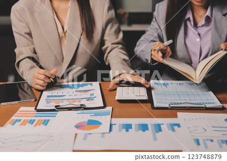 Group of confident business people point to graphs and charts to analyze market data, balance sheet, account, net profit to plan new sales strategies to increase production capacity. 123748879