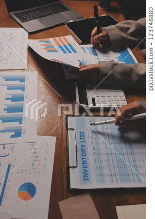 Group of confident business people point to graphs and charts to analyze market data, balance sheet, account, net profit to plan new sales strategies to increase production capacity. 123748880