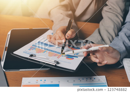 Group of confident business people point to graphs and charts to analyze market data, balance sheet, account, net profit to plan new sales strategies to increase production capacity. Group of confident business people point to graphs and charts to analyze market data, balance sheet, account, net profit to plan new sales strategies to increase production capacity. 123748882