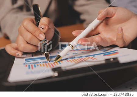 Group of confident business people point to graphs and charts to analyze market data, balance sheet, account, net profit to plan new sales strategies to increase production capacity. Group of confident business people point to graphs and charts to analyze market data, balance sheet, account, net profit to plan new sales strategies to increase production capacity. 123748883