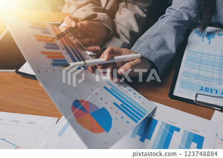 Group of confident business people point to graphs and charts to analyze market data, balance sheet, account, net profit to plan new sales strategies to increase production capacity. 123748884